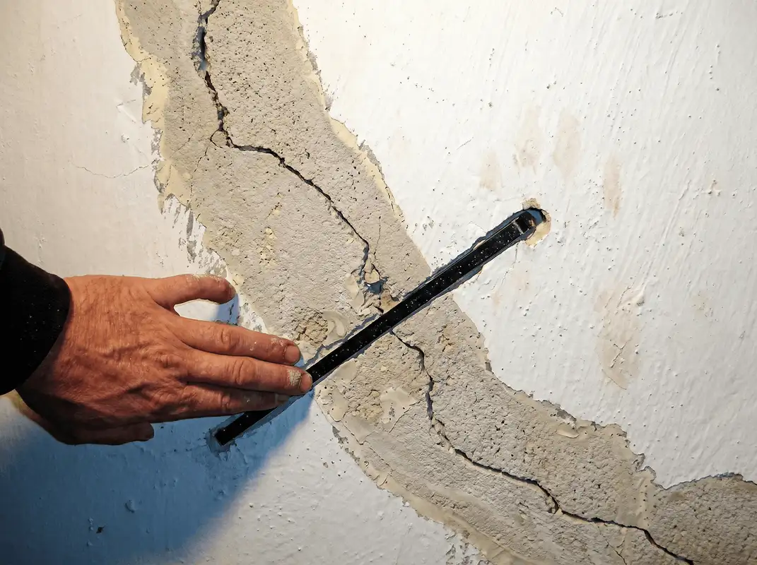 A wall with a large crack is being inspected by a professional in Scottsdale, AZ