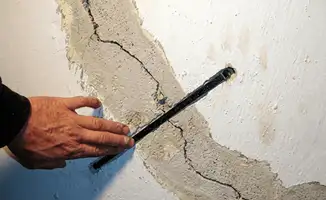 A wall with a large crack is being inspected by a professional in Scottsdale, AZ